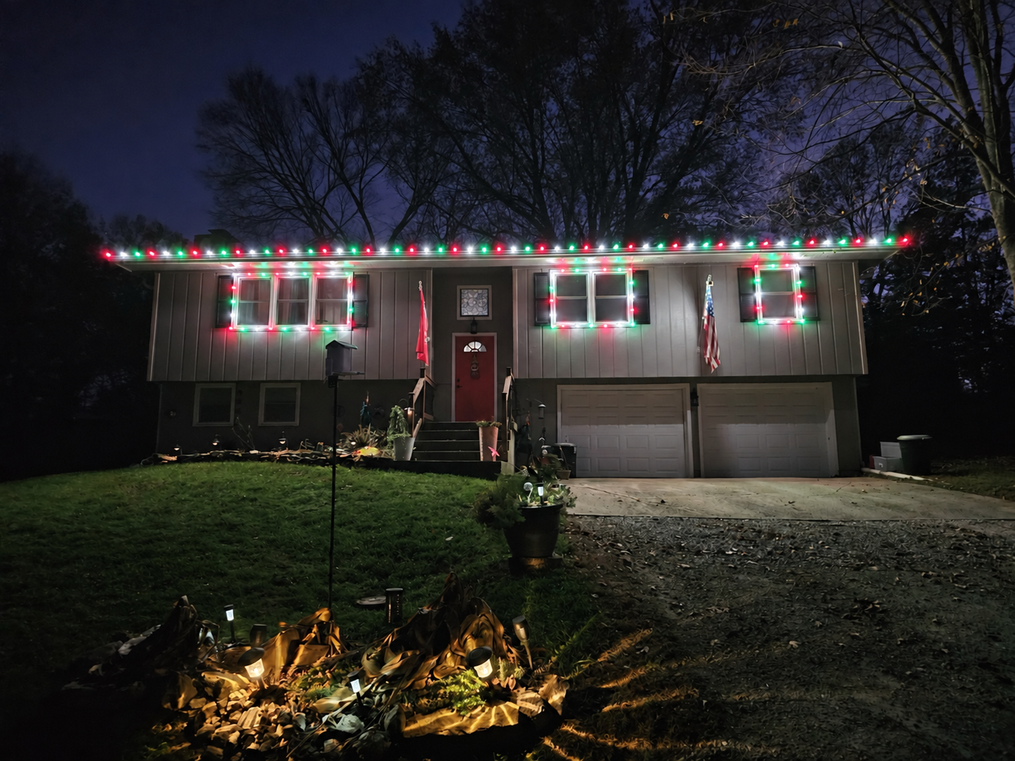 Split-level home with red, green, and white roofline and window Christmas lights