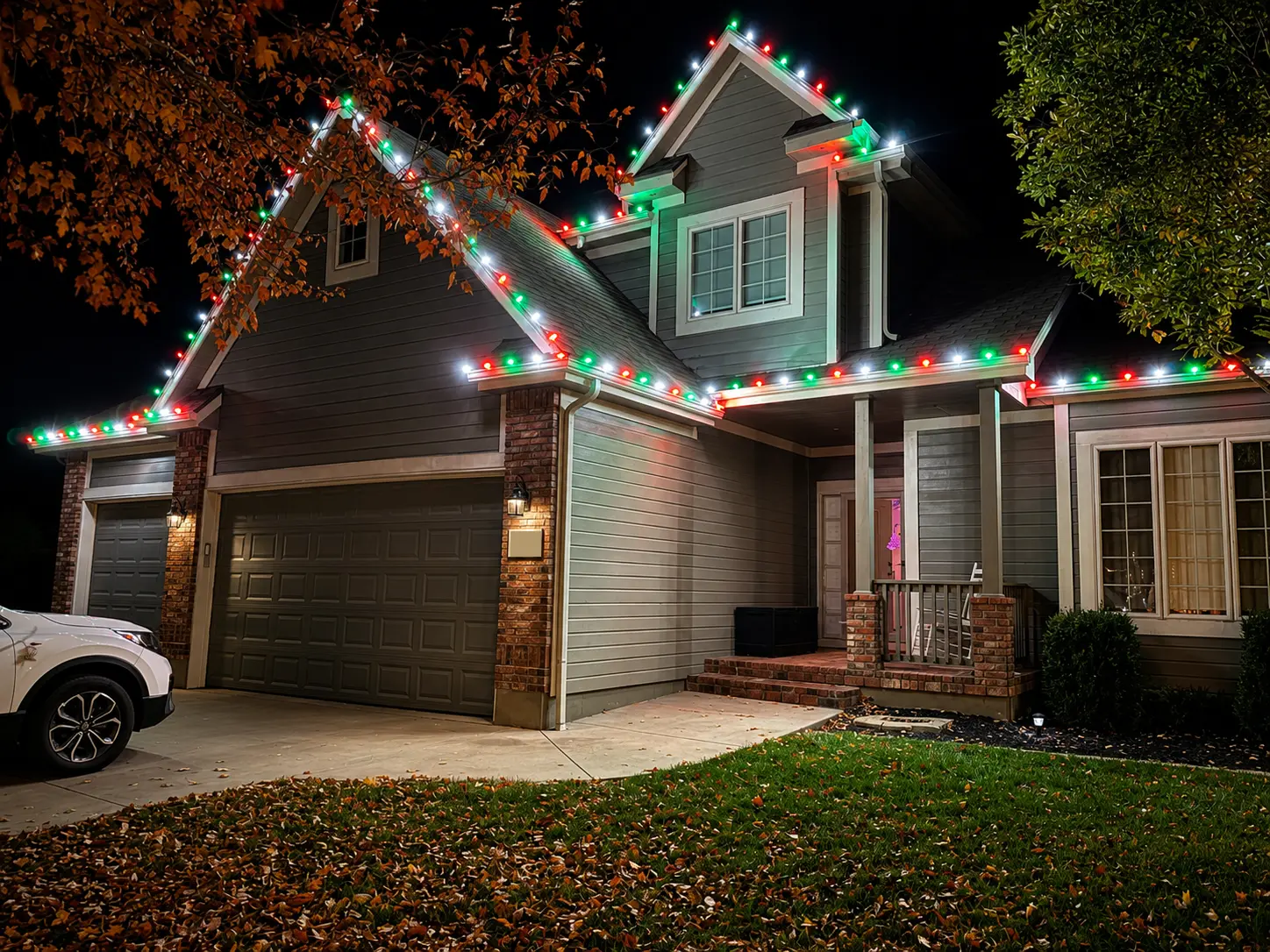 Brick and gray home outlined with red, green, and white Christmas lights