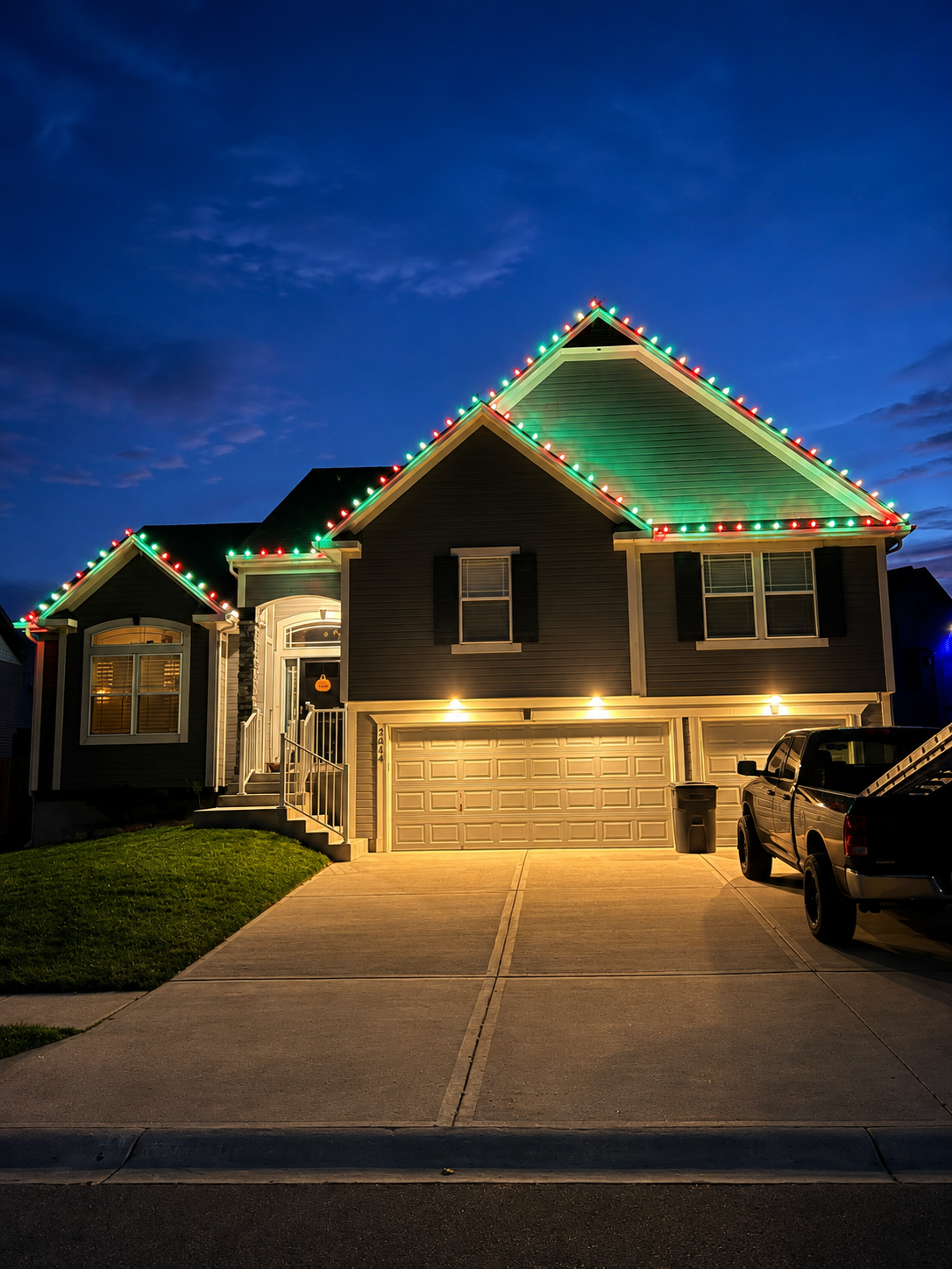 Home outlined in red and green Christmas lights at dusk